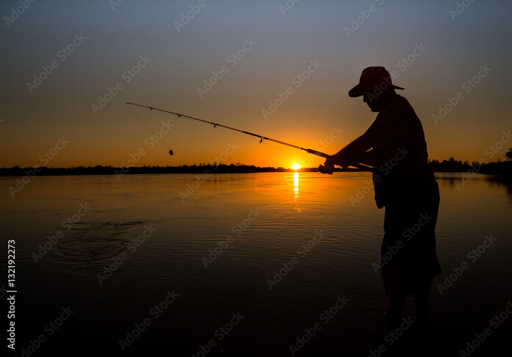 man fishing on a river from the boat at sunset