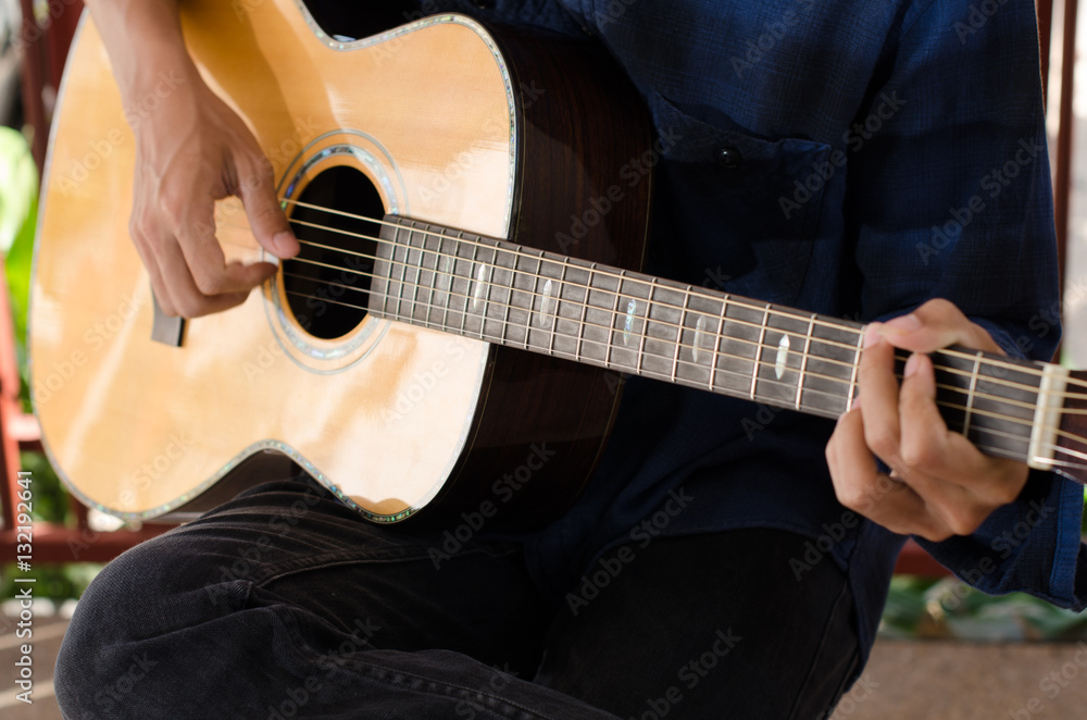 A young man playing acoustic guitar happy and relaxed in the day