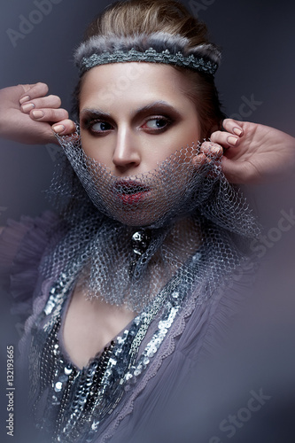 Beautiful girl in the image of the cold Queen with frost on his eyebrows. The model with creative makeup and crown on his head. Winter image in blue-violet tones. Beauty face. Photo in the fog.