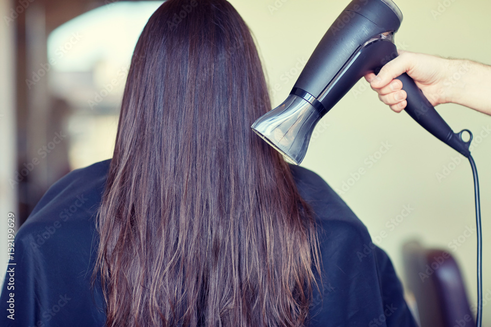 Fototapeta premium stylist hand with fan dries woman hair at salon