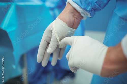Male surgeon removing surgical gloves in operation theater
