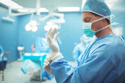 Fototapeta Male surgeon wearing surgical gloves in operation theater