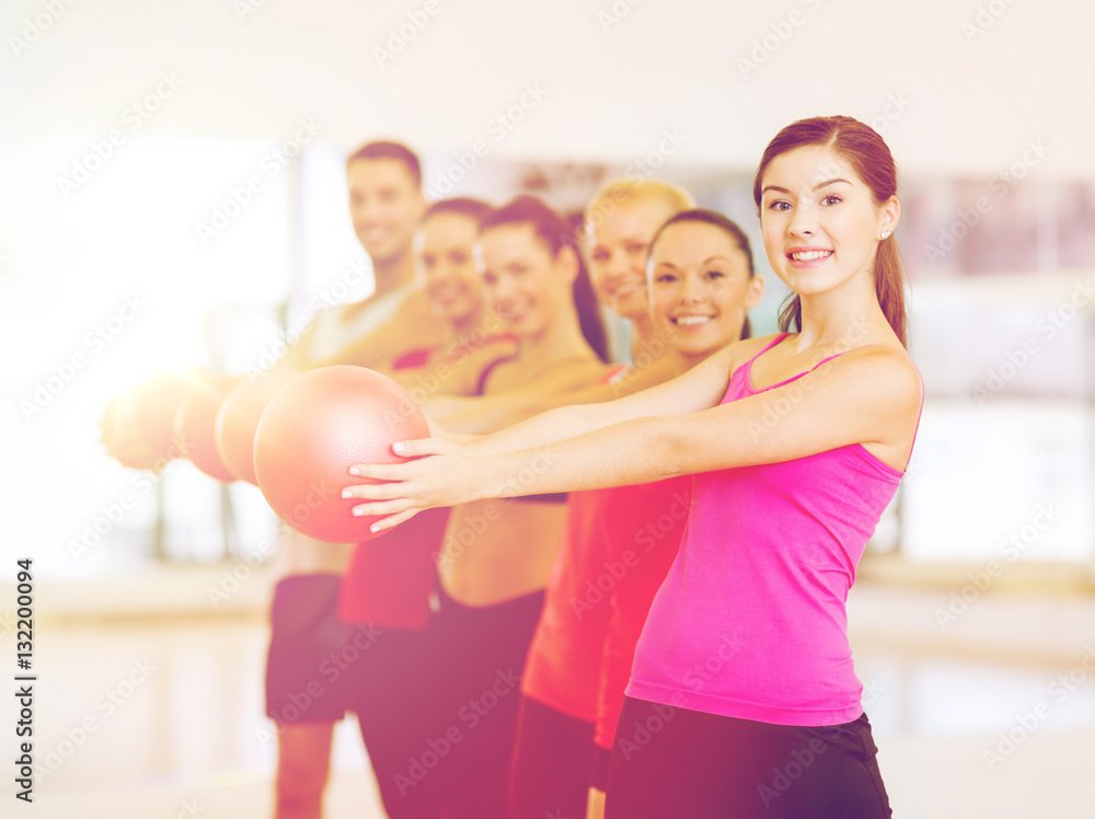 group of smiling people working out with ball