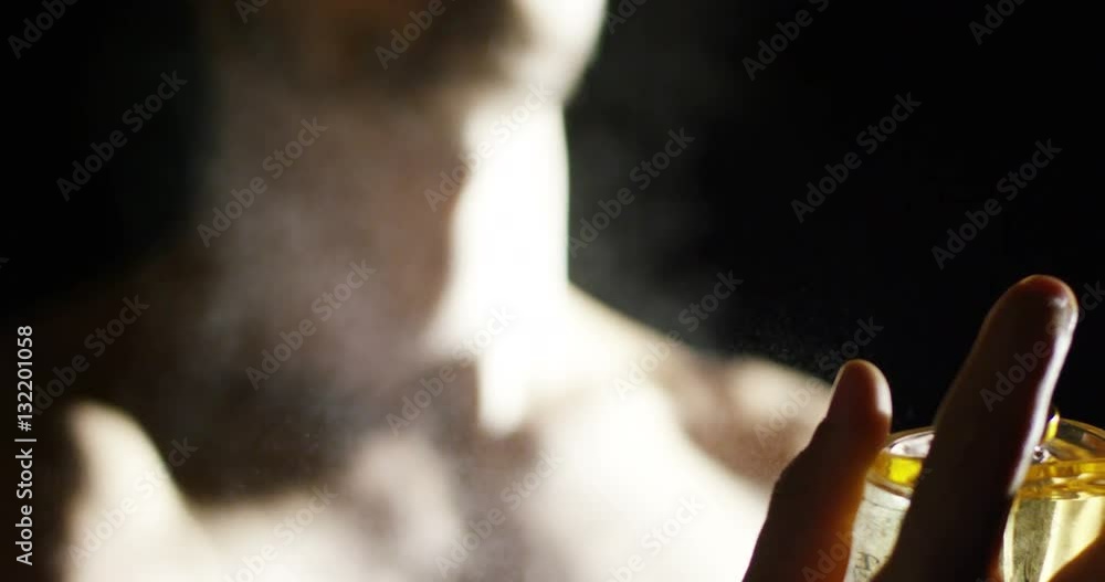 anonymous man spraying fragrance in extreme slow motion, with scent particles to wet skin after showering. anonymous man spraying fragrance in extreme slow motion, with scent particles to wet skin after showering.