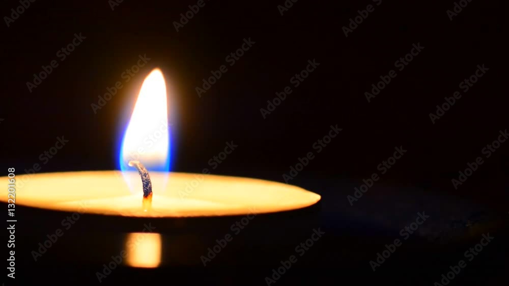 Closeup of burning wax candle on dark black background. The peaceful and tranquil atmosphere. Ideal for meditation. Closeup of burning wax candle on dark black background. The peaceful and tranquil atmosphere. Ideal for meditation.