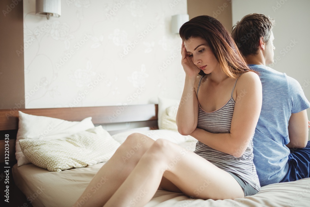 Couple ignoring each other sitting back to back on bed Couple ignoring each other sitting back to back on bed