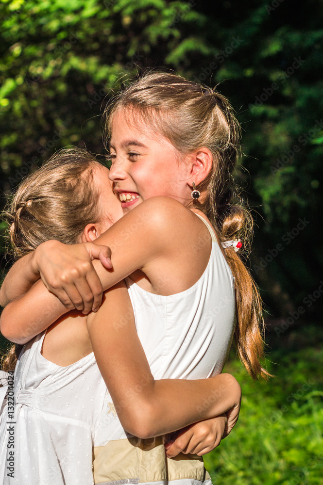 Fototapeta premium two beautiful daughters hugging and dancing in the park