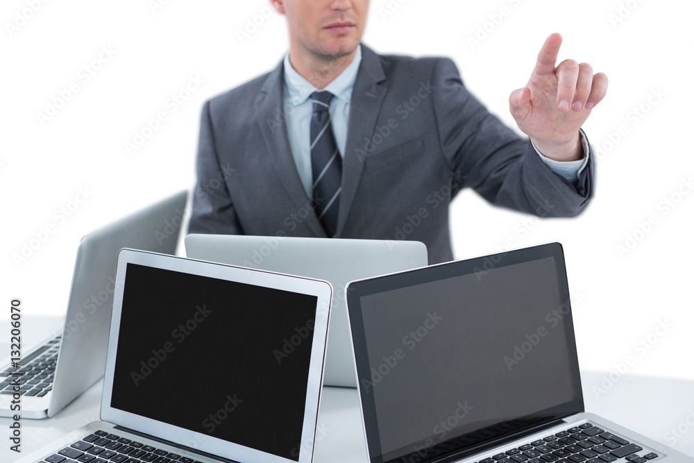 Businessman gesturing while sitting at table with four laptops Businessman gesturing while sitting at table with four laptops