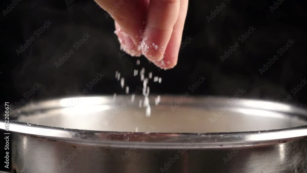 Add a salt to boiling water in pot, slow motion Add a salt to boiling water in pot, slow motion