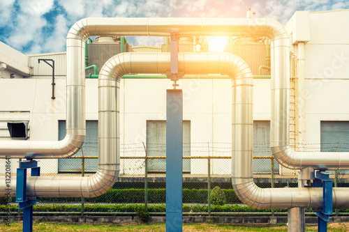 Loop steam pipeline on cooling tower background and sunshine.