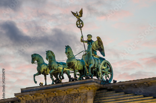 Detail of sculptures on top of Brandenburger Tor in Berlin with pink evening light and soft clouds, Germany photo