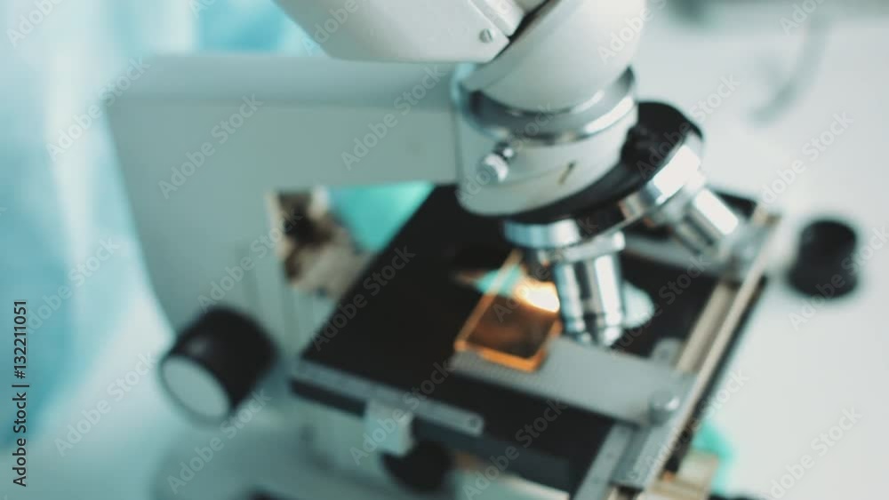 Middle age female scientist in uniform and medical face mask doing microscopic examination in laboratory. Middle age female scientist in uniform and medical face mask doing microscopic examination in laboratory.