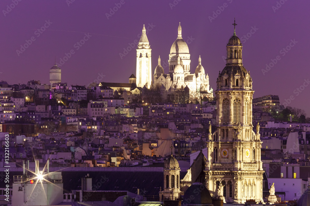 Aerial view of Sacre-Coeur Basilica or Basilica of the Sacred Heart of Jesus at the butte Montmartre and Saint Trinity church at night, Paris, France