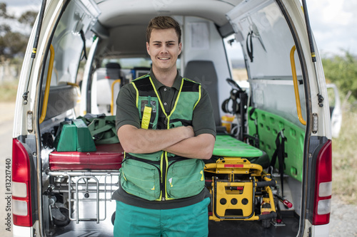 Paramedic standing with arms crossed in front of ambulance photo