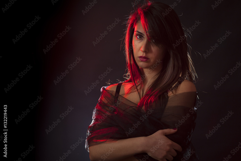 Beauty portrait of a young brunette girl with veil. Red backlight, black background Beauty portrait of a young brunette girl with veil. Red backlight, black background