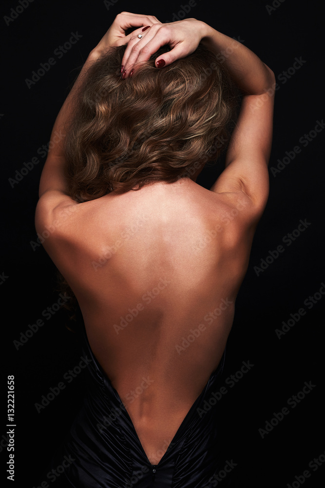 Fototapeta premium beautiful back of young woman in a black sexy dress.beauty brunette Girl with curly healthy hair