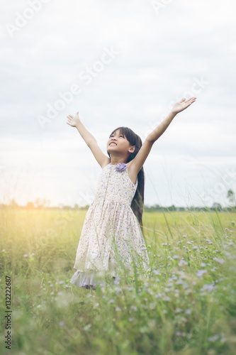 Cute Asian Girl raised hand at meadow happily.