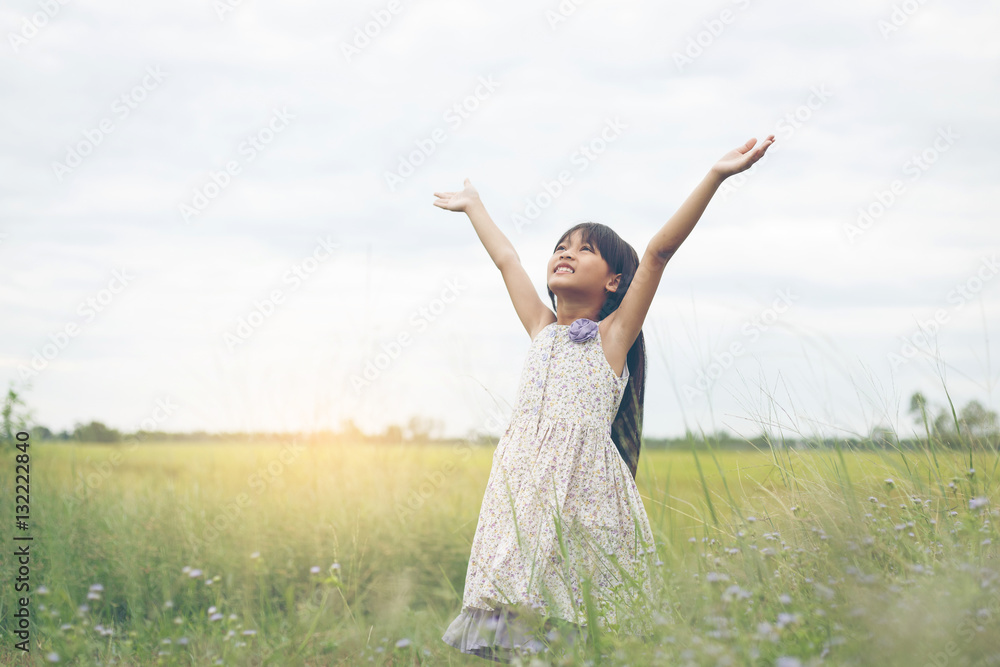 Cute Asian Girl raised hand at meadow happily. Cute Asian Girl raised hand at meadow happily.