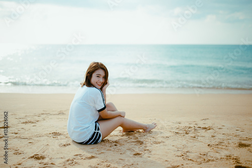Bueatiful girl sit on the beach.