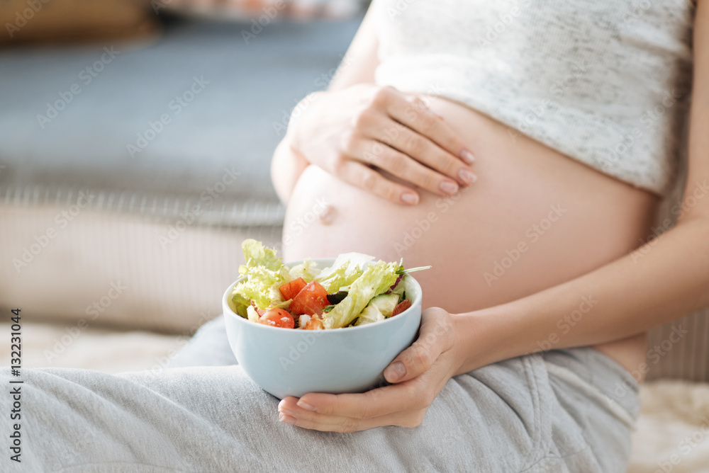 Close up of pregnant woman holding a salad