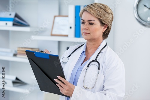 Female doctor writing on clipboard