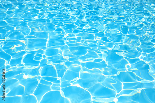 Blue water surface in swimming pool with sun reflection