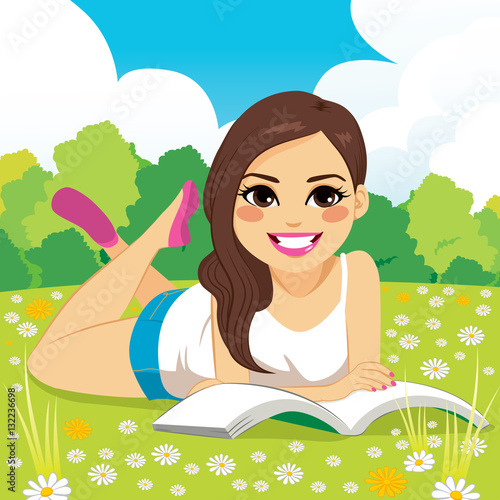 Beautiful brunette latina woman lying down on grass reading book in park