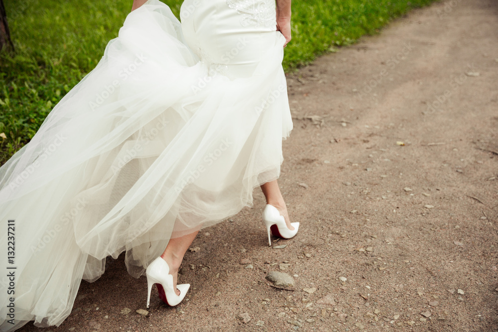Beautiful bride's shoes with long legs in white wedding dress Beautiful bride's shoes with long legs in white wedding dress