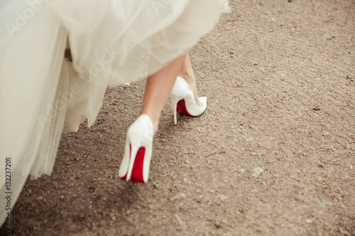 Beautiful bride's shoes with long legs in white wedding dress