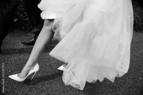 Beautiful bride's shoes with long legs in white wedding dress