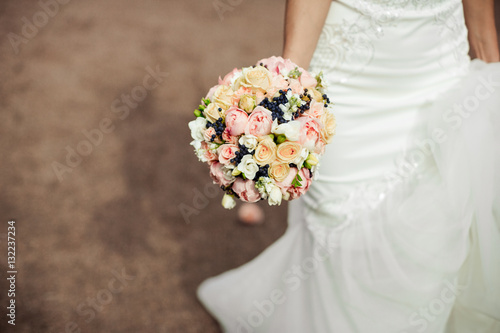 beautiful tender wedding bouquet of roses and eustoma flowers in hands of the bride