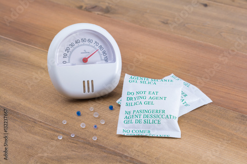 Desiccant or silica gel in white packaging and hygrometer on woo