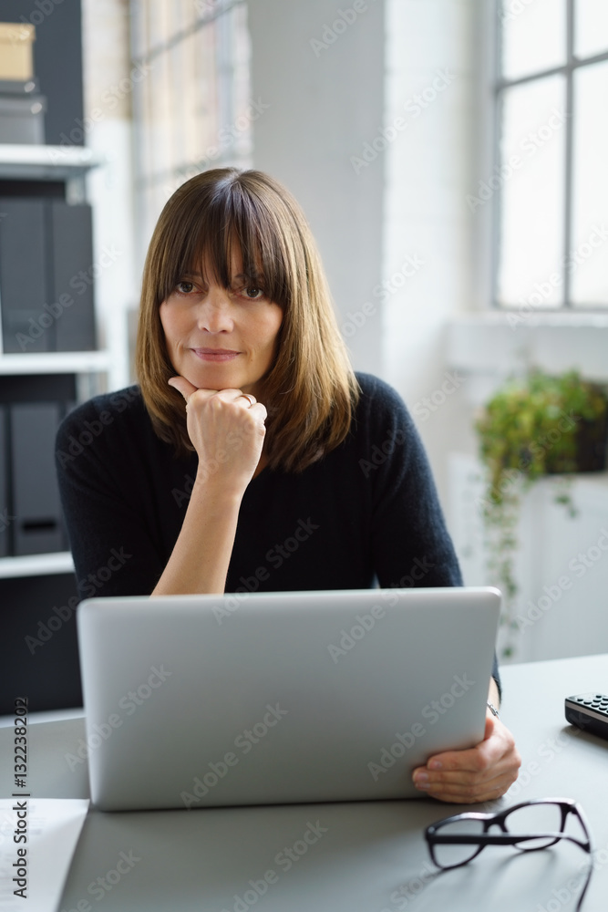 nachdenkliche frau arbeitet am laptop und stützt den kopf auf