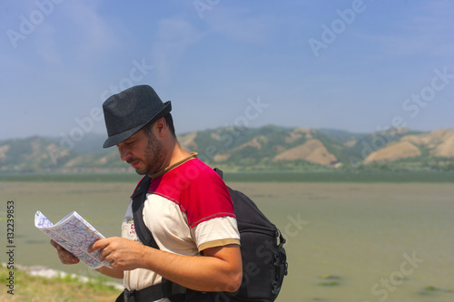 Camper,tourist in nature by the river looking at his map