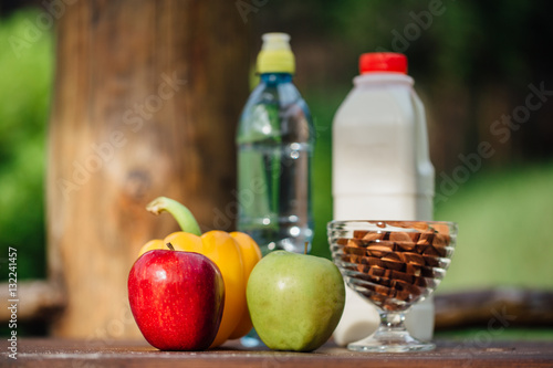assorted fresh vegetables, peppers, apples, water and milk on wooden table. yoga, life concept, healthy eating food.