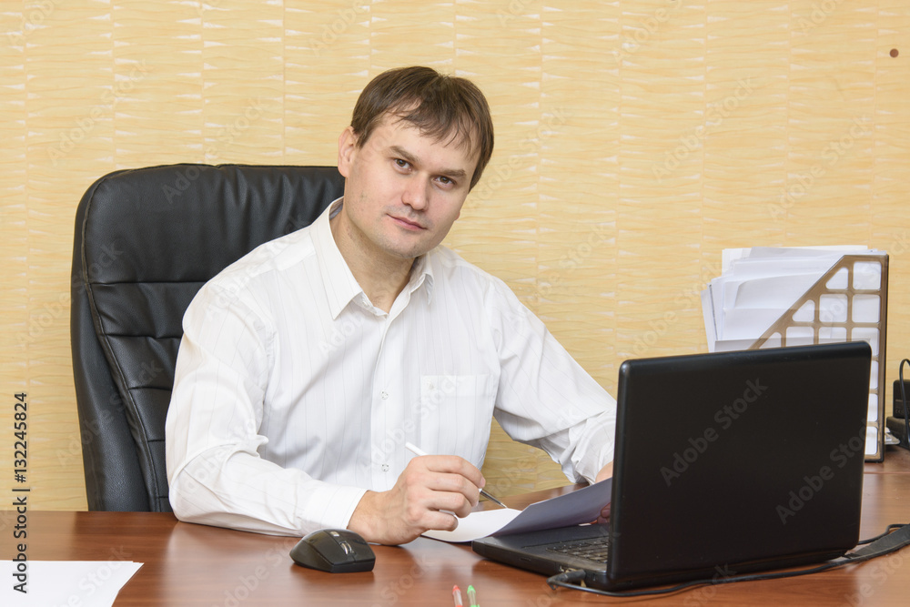 The man at the desk in the office at the computer to view the document The man at the desk in the office at the computer to view the document