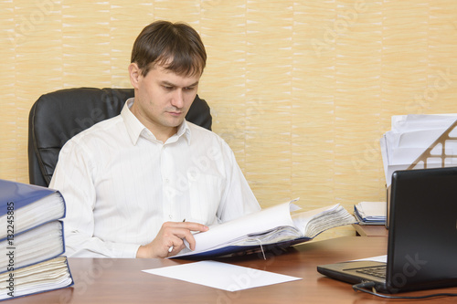 The man at the desk in the office to view documents