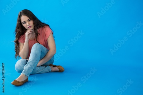 Beautiful woman sitting against blue background