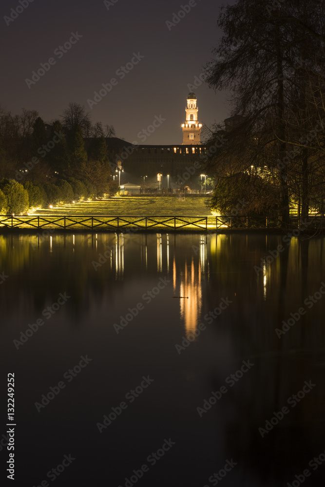 Night view of the Parco Sempione large central park in Milan, Italy. The Sforza Castle (Castello Sforzesco) in the background.