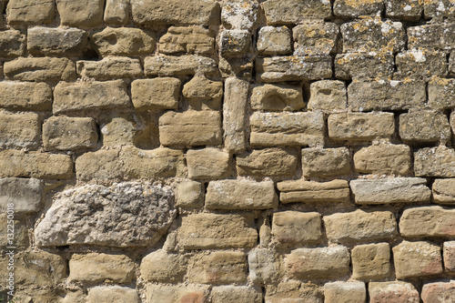 Old stone wall of a castle carved by hand with some more modern pieces in the upper right