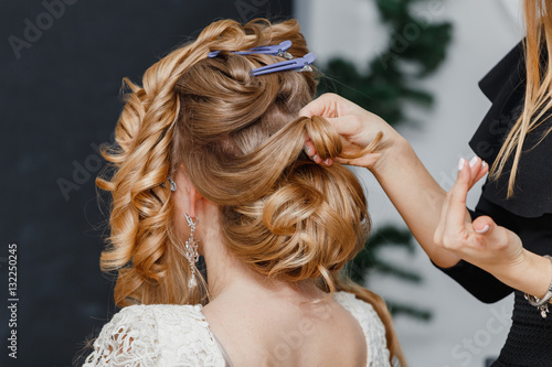 Young bride getting her hair done before wedding by professional hair stylist