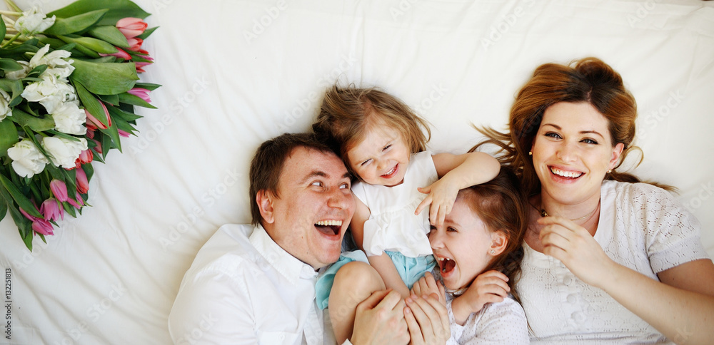 Big close-knit family from four people cheerfully spends time for beds