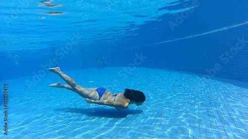 young girl swimming underwater in a blue pool under water gopro