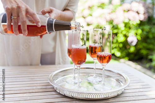 Woman pouring sparkling wine into four glasses photo