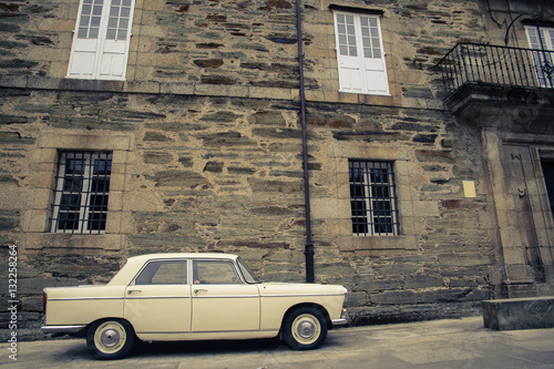 Old antique car with stone wall in background