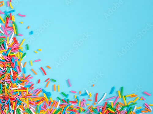 Border frame of colorful sprinkles on blue background photo