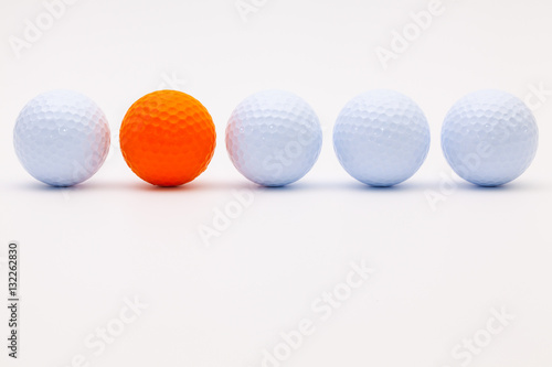 White and orange golf balls on the white desk