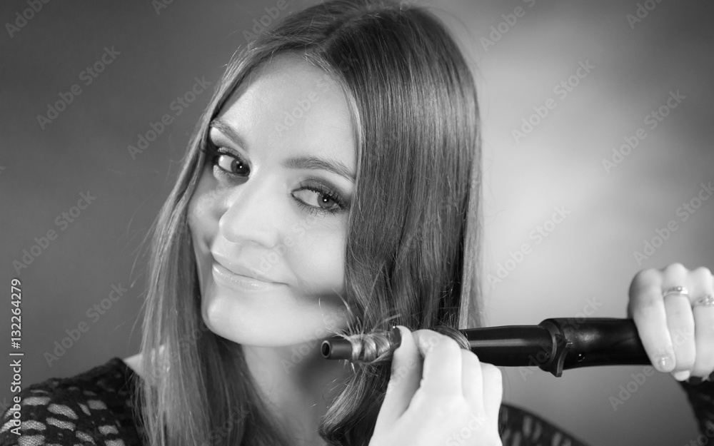 Obraz premium Happy woman curling her long brown hair