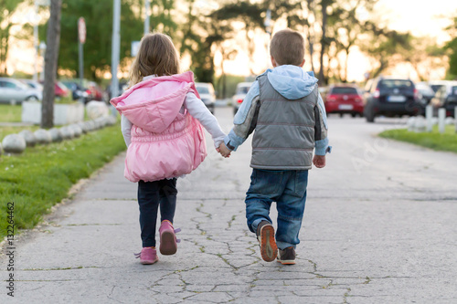 Litle boy and girl walking together and holding hands