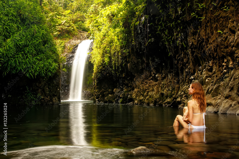 Fototapeta premium Young woman sitting at Wainibau Waterfall on Taveuni Island, Fij